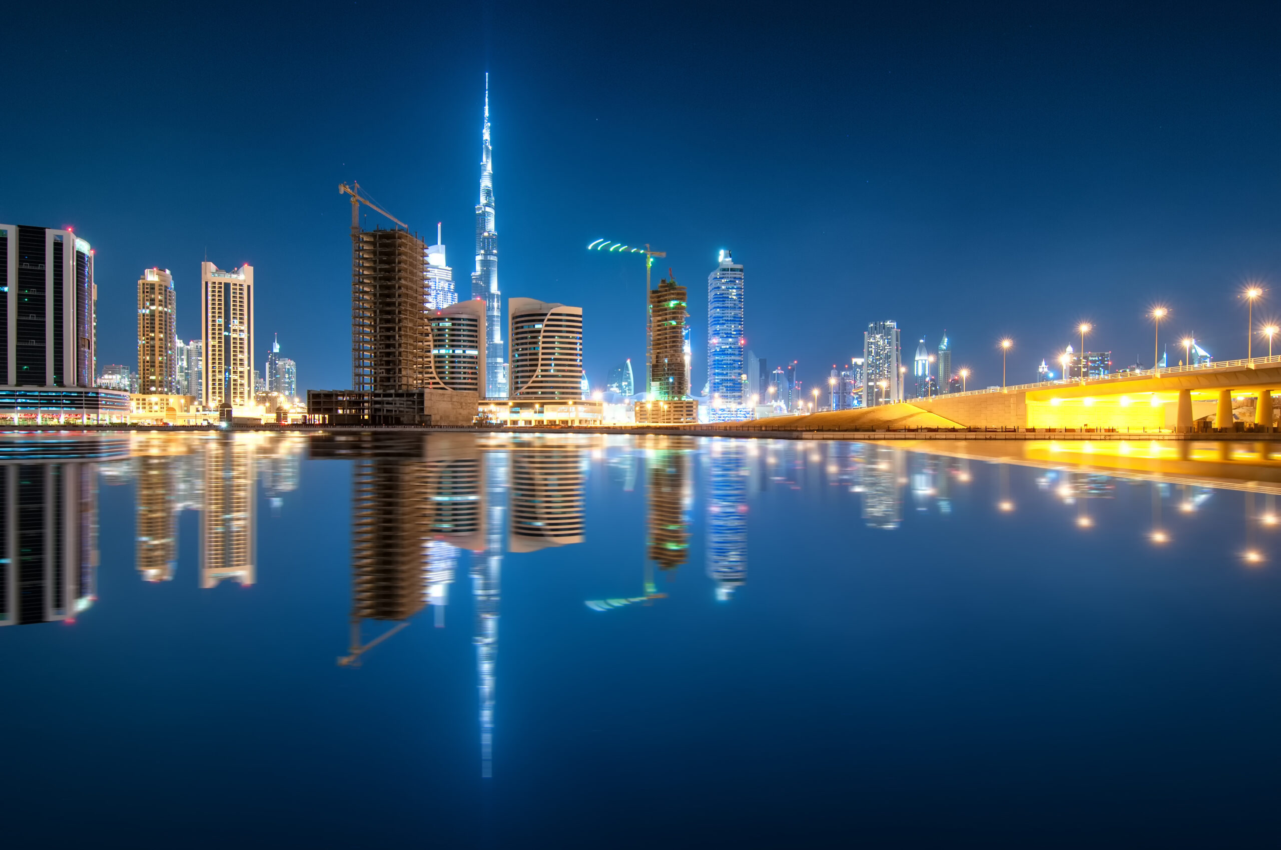 Fascinating reflection of tallest skyscrapers in Business Bay district during calm night. Downtown summer night. Construction built at night time. Dubai, United Arab Emirates.