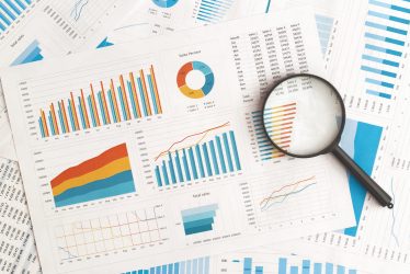 Business graphs, charts and magnifying glass on table. Financial development, Banking Account, Statistics