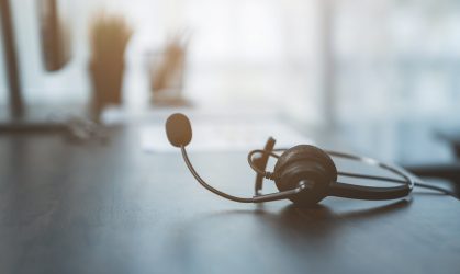 VOIP headset of customer support phone operator at workplace on desk.