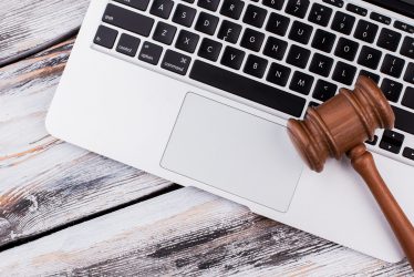 Wooden court gavel on a laptop keyboard. Old white wooden table.