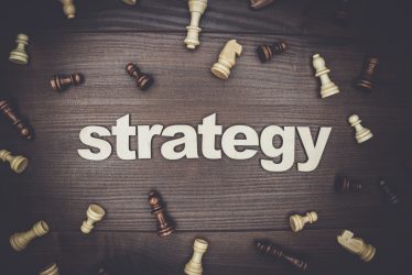 word strategy and chessmen on the brown wooden background
